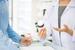 Pharmacist giving bottle of drugs to a customer in a pharmacy