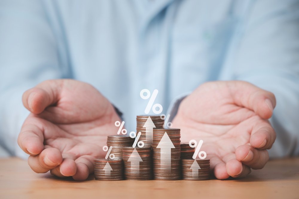 A person stacking coins representing the high rate of return due to high interest rates, potentially due to usury.