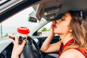 Mujer aplicando maquillaje de manera imprudente mientras conduce un coche