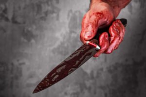 Male hand with bloody knife over concrete wall