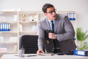 Hombre en traje de negocios robando un secreto comercial del escritorio de otra persona