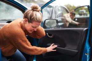 Woman holding her injured neck in her car after a sideswipe accident