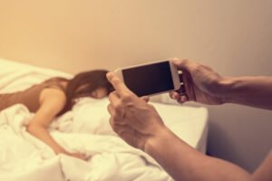 Hand man holding phone to photograph woman in bed as blackmail in violation of NRS 205.320 