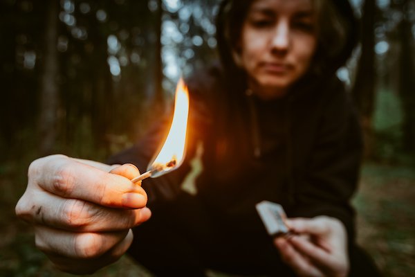 Person lighting match in forest