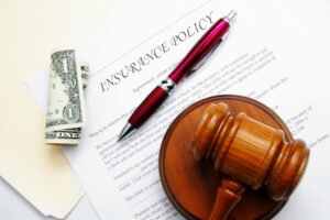 Gavel, cash, and paper that says "insurance policy"