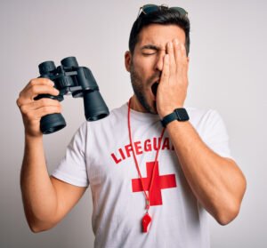 Sleepy lifeguard holding binoculars