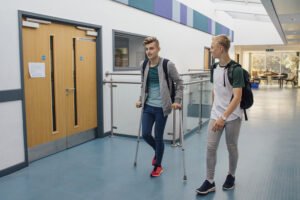 Student in crutches walking to class at college