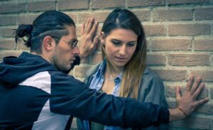 Man cornering a woman against a brick wall
