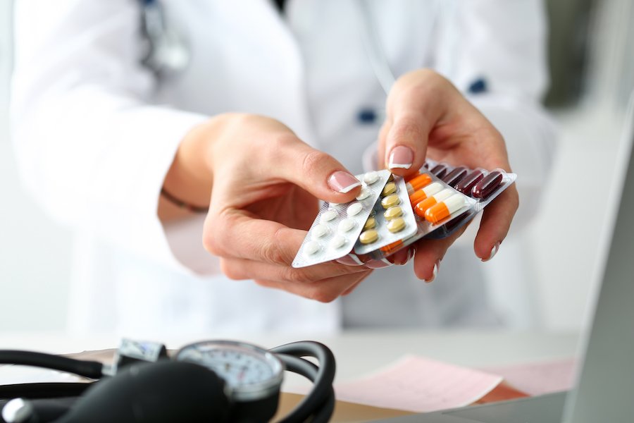 Doctor's hands holding an assortment of prescription pills