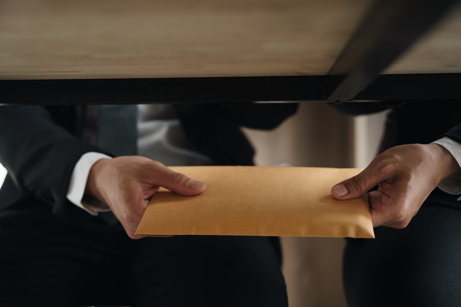 Man passing a bribe under the table