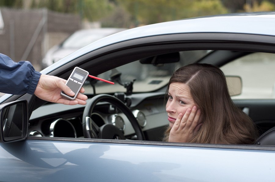 Woman in front seat of car about to take a breath test