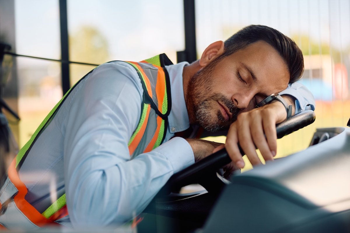 Fatigued bus driver sleeping on wheel